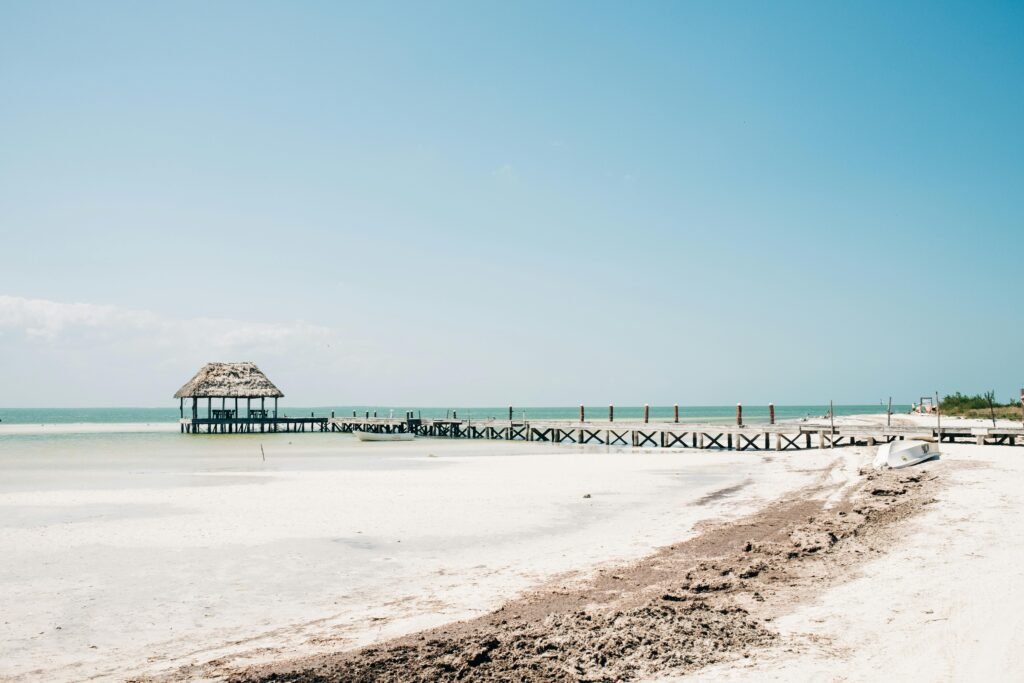 Serene beach scene featuring a rustic pier and tranquil waters in Holbox, Mexico.