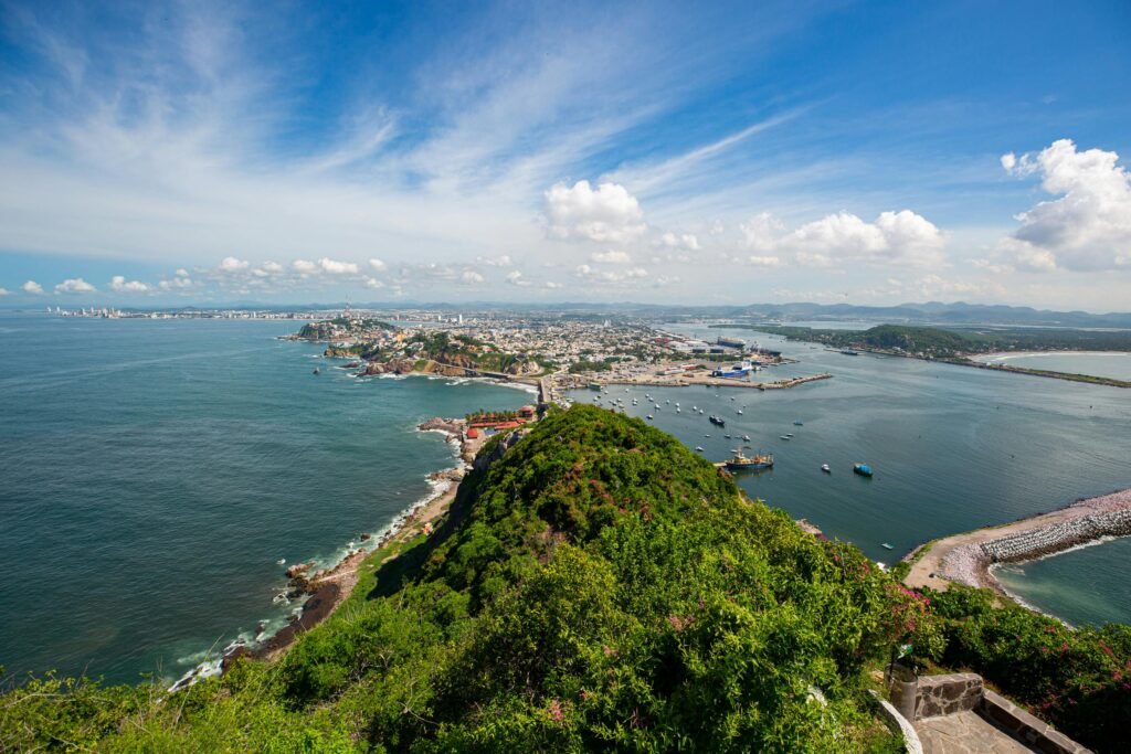 Stunning aerial view of Mazatlán's coastline, featuring the vibrant city, lush hills, and blue ocean.