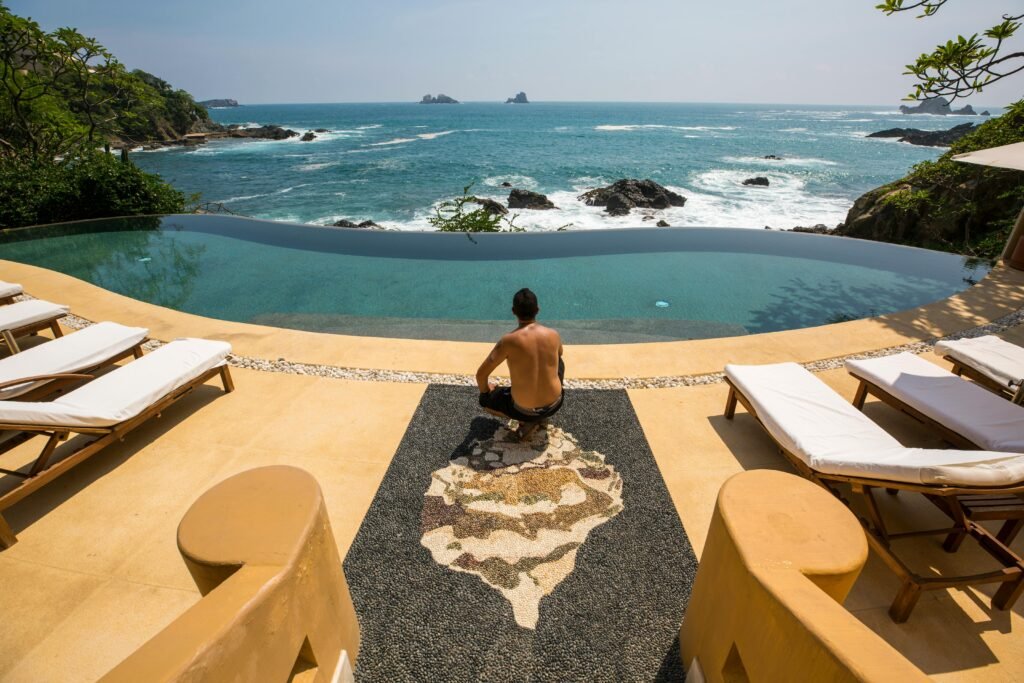 Man relaxing by an infinity pool overlooking the ocean in Zihuatanejo, Mexico.