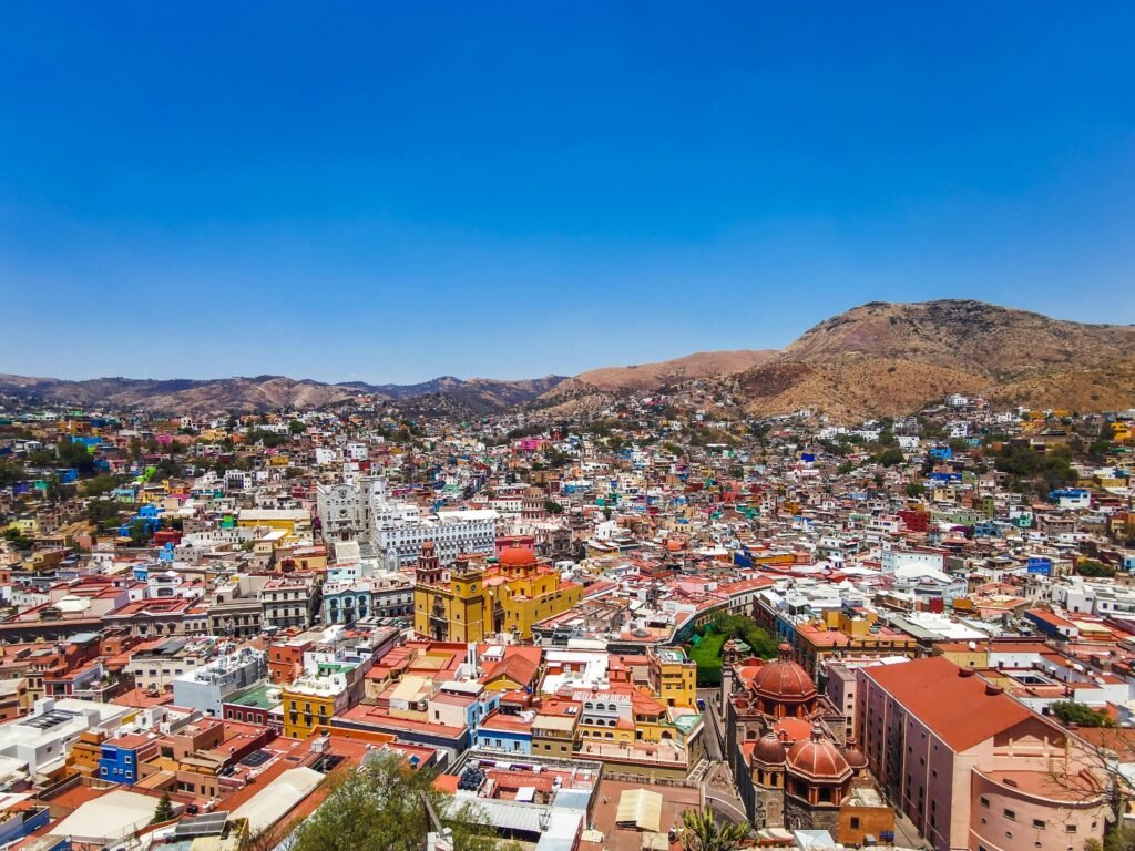Aerial view of colorful colonial architecture in Guanajuato, Mexico under a clear blue sky.