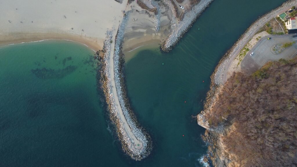 Drone shot capturing the stunning coastline of Crucecita, Oaxaca, revealing a vibrant blue sea and rugged shorelines.