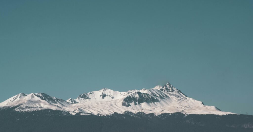 A breathtaking view of snow-capped mountain peaks under a clear blue sky, perfect for winter travel inspiration.