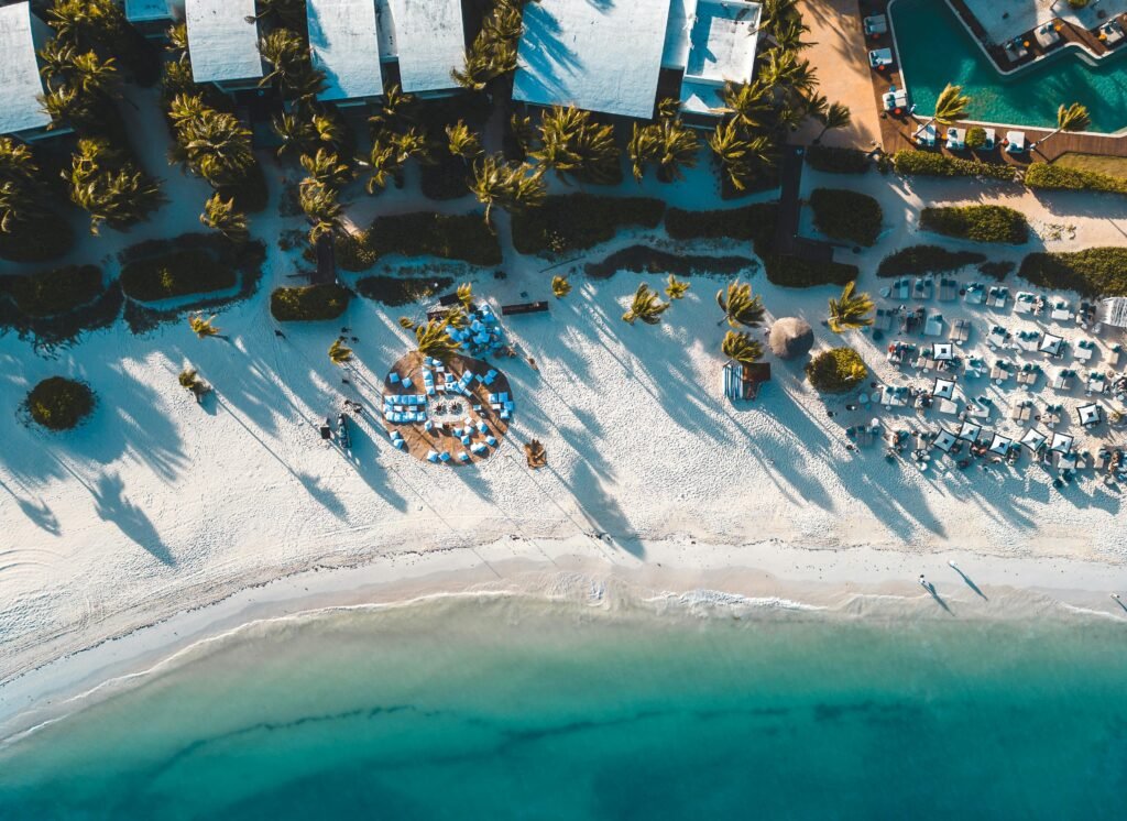 Stunning aerial view of a tropical beach resort in Playa del Carmen, Mexico with palm trees and clear blue waters.