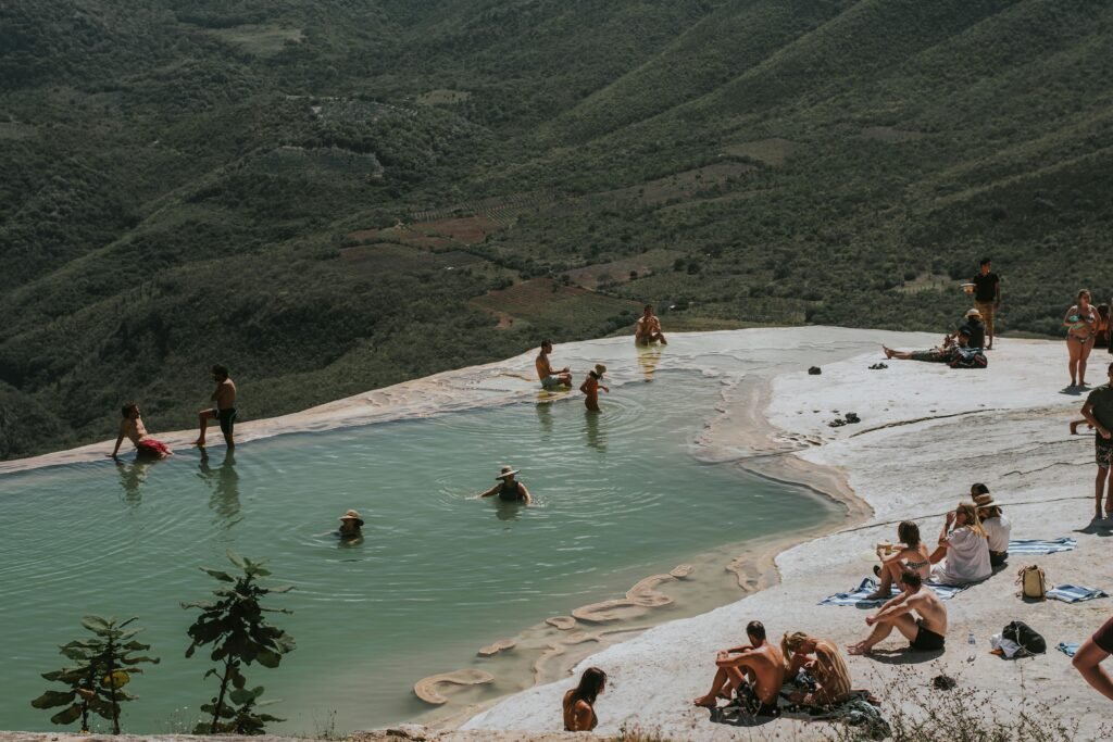People relax in a natural infinity pool with a stunning mountain backdrop, ideal for summer tourism and travel.