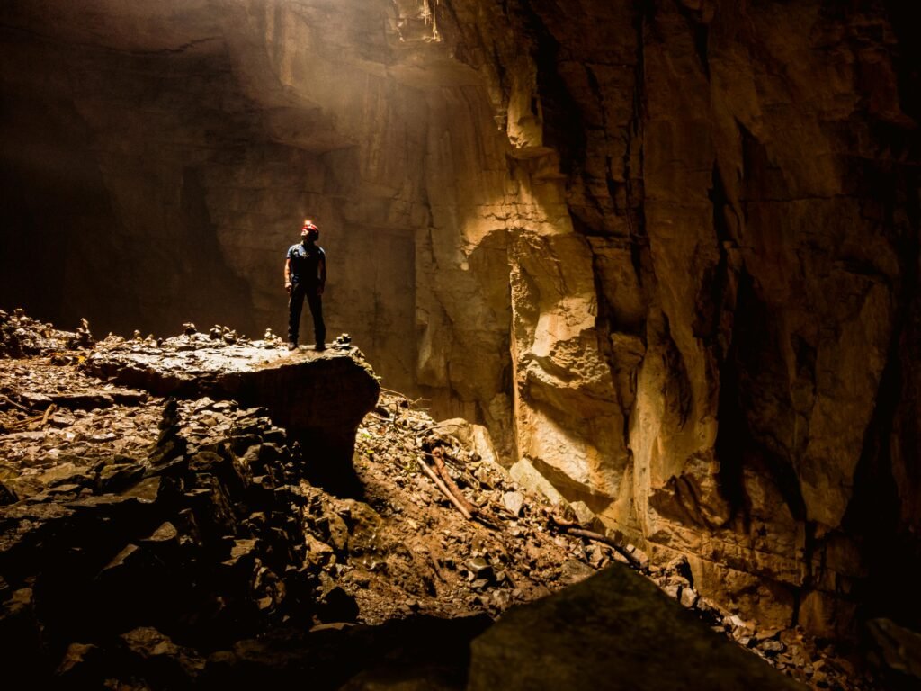 A lone explorer stands illuminated by a beam of light in a mysterious cave in Cuetzalan, Mexico.