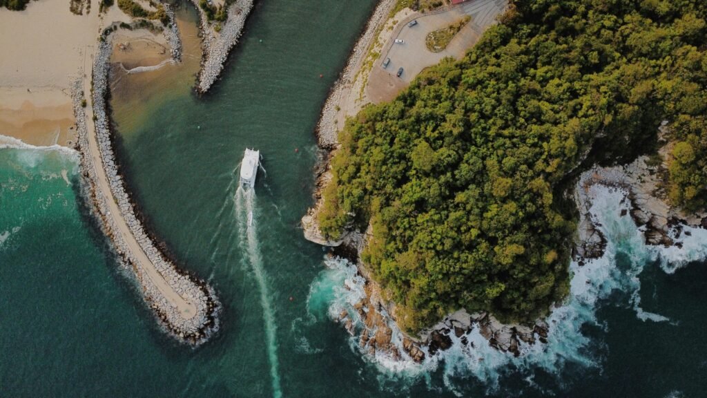 Stunning aerial view of Mazunte's coastline with a boat navigating through the turquoise sea and lush greenery.