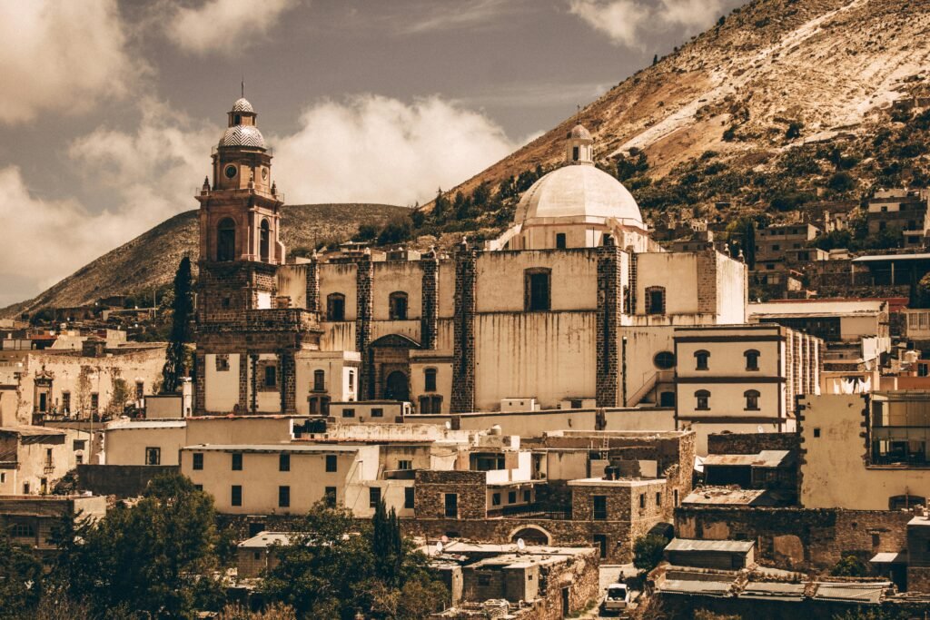 Explore the stunning colonial architecture of a Mexican town with its iconic domed church and scenic mountain backdrop.