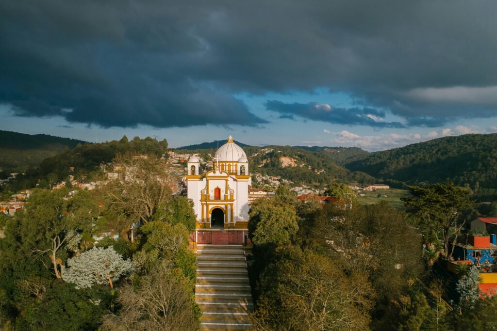 Aerial view of a church in San Cristóbal de las Casas, Mexico, surrounded by lush greenery.